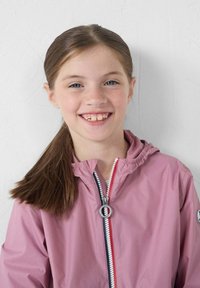 Lichtroze jas met een capuchon, voorzien van een rits aan de voorkant met rode en marineblauwe details, en een ronde zilveren trekhaakaccent.