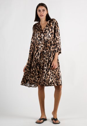Leopardenmuster-Kleid aus leichtem Stoff, mit V-Ausschnitt, 3/4-Ärmeln und gestuftem Rockdesign, kombiniert mit schwarzen Flip-Flops.