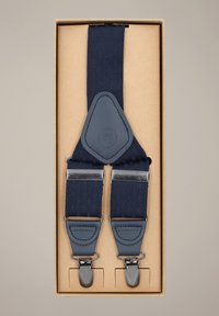 Granatowe szelki z teksturowanymi paskami, skórzanymi akcentami i metalowymi klipsami. Zapakowane w brązowe pudełko.