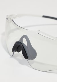 Klare Sportbrille mit einem leichten Rahmen, ausgestattet mit einem schwarzen Nasenpolster und einem eleganten, umschlossenen Design für verbesserte Sichtbarkeit und Schutz.