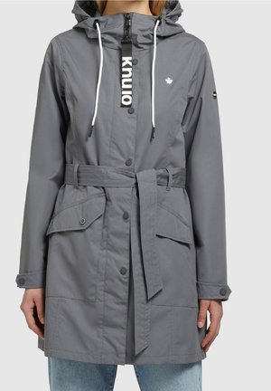 Imperméable gris à capuche avec cordons blancs, boutons à l'avant, ceinture à la taille, poches à rabat et petit logo blanc en forme de feuille d'érable sur la poitrine.