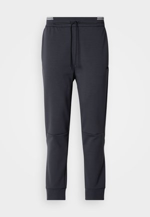 Dunkelgraue Sweatpants mit Kordelzugbund, schmal zulaufenden Beinen und Seitentaschen. Glatte Textur und minimalistische Designdetails.