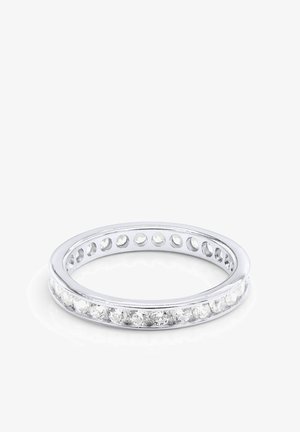 Bague anneau en argent avec une rangée continue de pierres précieuses rondes claires serties tout autour de l’anneau sur fond blanc.