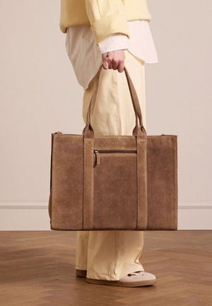 Braune Leder-Tote mit zwei langen Griffen, einer vorderen Reißverschlusstasche und minimalistischer Gestaltung. Glatte Textur und rechteckige Form.