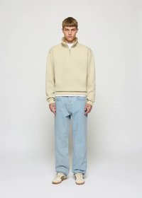 Camisola de lã confortável com fecho éclair, jeans azul-claro de perna reta e ténis bege. Design simples com acabamento texturizado e punhos canelados.