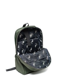 Zielony plecak z gładką zewnętrzną powierzchnią. Wnętrze wyściełane granatową podszewką z jasnym nadrukiem przedstawiającym zawodnika polo. Zawiera zamykaną na suwak komorę.