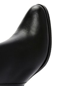 Black leather shoe with a pointed toe and smooth texture. Features a slight heel and minimal stitching detail along the side.