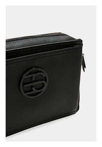 Borsa nera in pelle con texture, dotata di una cerniera orizzontale e un logo circolare nero sul pannello frontale.