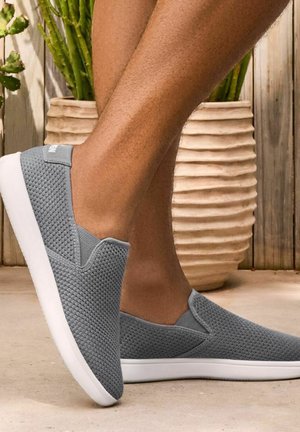 Grau slip-on Schuhe aus strukturiertem Mesh-Material, mit einer weißen Gummisohle und dezentem Branding an der Ferse.