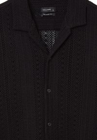 Chemise noire à manches courtes en tissu texturé avec une coupe décontractée, présentant un devant à boutons et des détails en tricot à motifs.