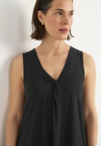 Schwarzes ärmelloses Kleid mit V-Ausschnitt und einer verdrehten Knotendetail vorne, aus einem weichen, glatten Stoff gefertigt.