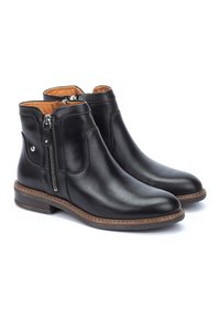 Bottes chelsea en cuir noir avec des fermetures éclair sur les côtés, semelle marron et texture lisse. Présente un doublure beige contrastante et des coutures décoratives.