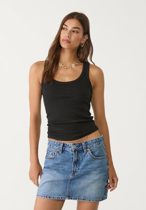 Top a righe nera senza maniche con scollatura tonda abbinato a una gonna mini in denim azzurro chiaro caratterizzata da una chiusura a bottoni e tasche frontali.
