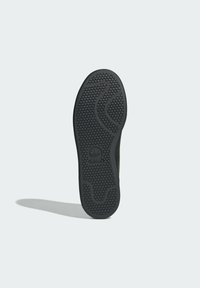 Czarna podeszwa zewnętrzna sneakersa z teksturowanym wzorem plastra miodu, wyposażona w elastyczne rowki oraz wytłoczone logo na pięcie.