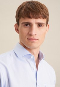 Lichtblauw overhemd met kraag, gladde textuur en subtiele glans. Heeft een borstzak en bijpassende knopen.