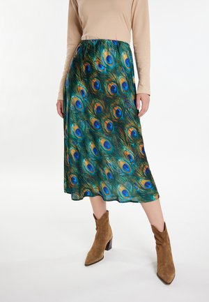Gonna midi con un motivo a piuma di pavone nei toni del verde, blu e oro; realizzata in tessuto leggero, abbinata a stivali alla caviglia in suede color nocciola.