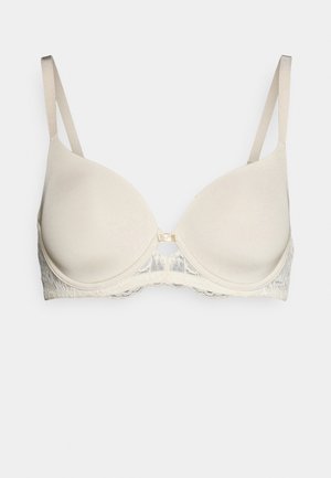 Beige padded bra with lace trim, featuring adjustable straps and a central metal clasp. Smooth fabric with a textured lace back.