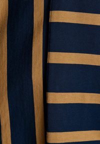 Close-up of fabric with alternating navy blue and tan vertical and horizontal stripes, showing texture and knit pattern.
