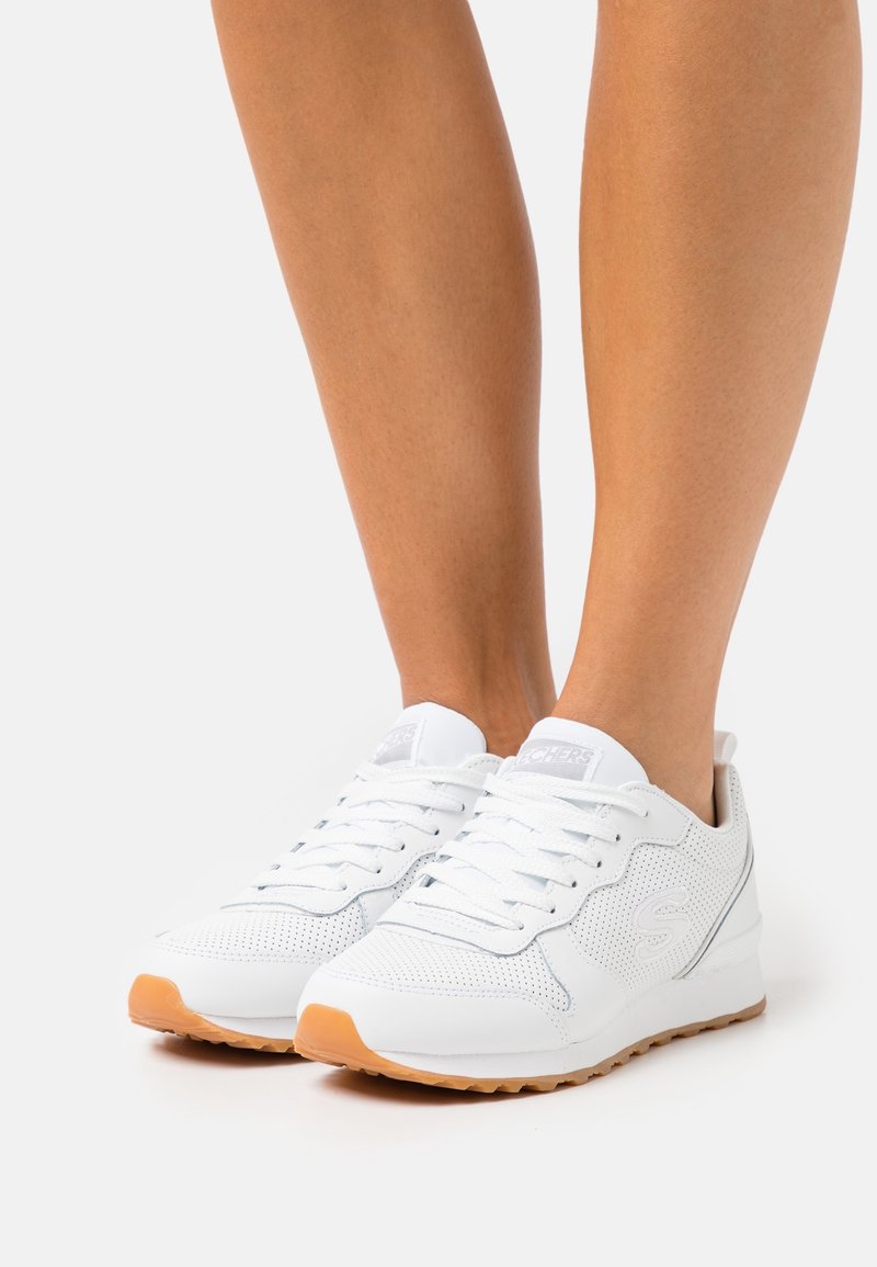 White athletic shoes with a mesh upper and smooth leather accents, featuring a light-colored rubber sole and decorative logo on the side.