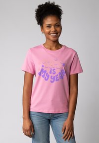 Roze katoenen T-shirt met paarse tekst "DIT is MIJN JAAR" met bloemenaccenten, korte mouwen en een ronde hals.