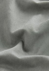 Tela gris con una textura suave y ligeramente brillante, que presenta pliegues suaves y fluidos, así como un sutil patrón acanalado.