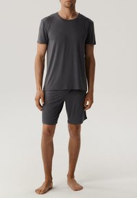 Szary bawełniany t-shirt z krótkim rękawem w zestawie z pasującymi szortami. Oba elementy są gładkie, dopasowane i mają okrągły dekolt oraz bezszwowy design.