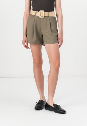 Olive green shorts with pleats and a wide beige woven belt featuring a rectangular buckle. Worn with black lace-up shoes.