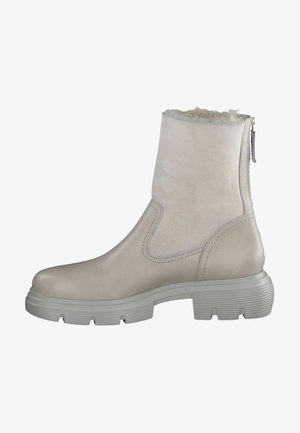 Jasnobeżowy kozaki sięgające do połowy łydki z grubą gumową podeszwą, zamkiem błyskawicznym po boku oraz miękką podszewką z polaru widoczną przy górnym otwarciu.