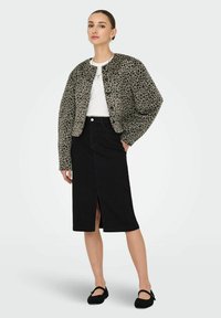 Chaqueta corta de estampado de leopardo, falda de mezclilla negra con apertura delantera, camiseta blanca y zapatos negros. Tela suave, corte relajado y patrón texturizado.