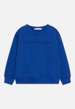 Sininen collegepaita, joka on valmistettu puuvillasekoitteesta. Siinä on pyöreä pääntie, resorit hihansuissa ja helmassa sekä edessä brodeerattu "Calvin Klein Jeans" -logo.