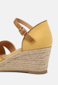 Yellow canvas wedge sandal with a brown adjustable strap and jute-wrapped sole. Rounded toe and textured upper for enhanced grip.