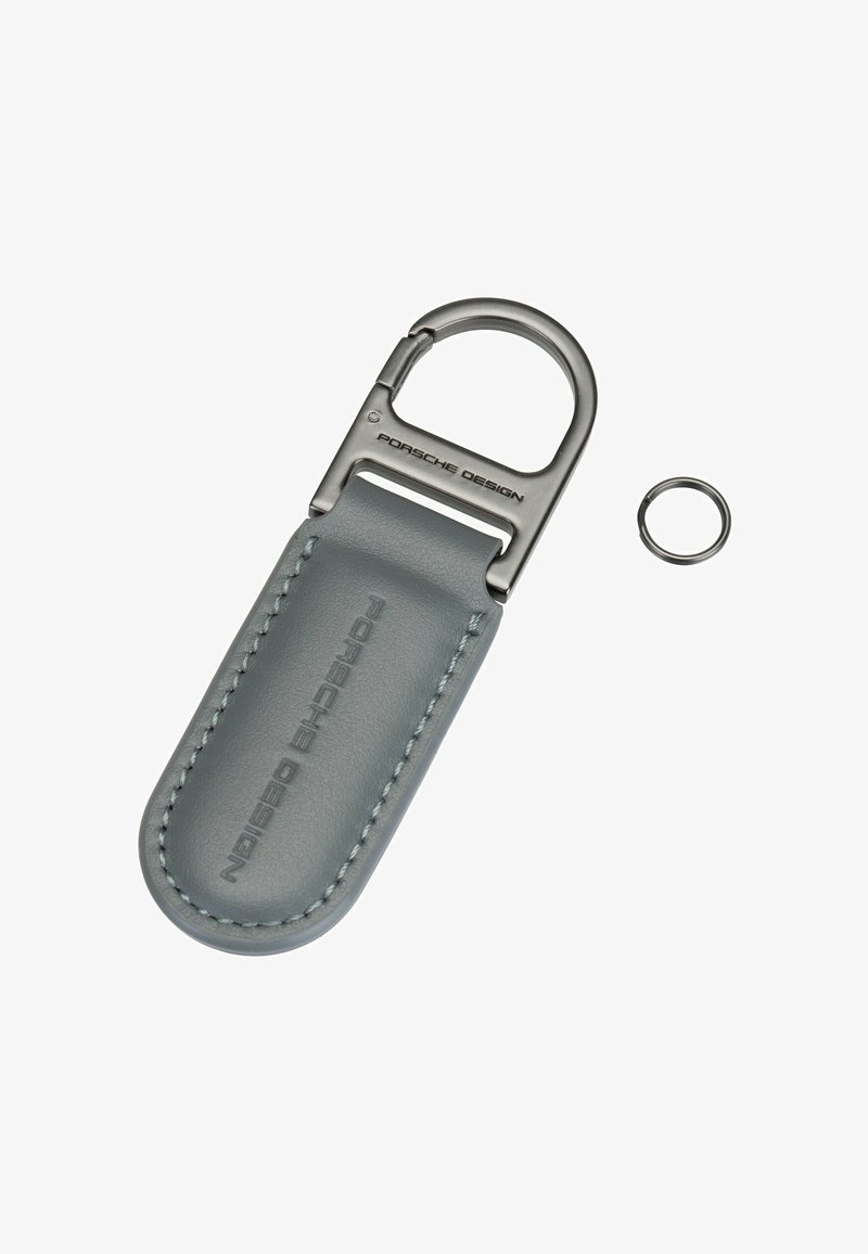 Porte-clés Porsche Design en cuir gris avec fermoir en métal et petit anneau métallique détaché sur fond blanc.