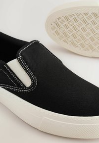 Musthave musta kangast slip-on king, millel on valged elastsed külgpaneelid ja õmblused. Valge kummitald, millel on tekstuuriga haardemuster. Sile ja vastupidav materjal.