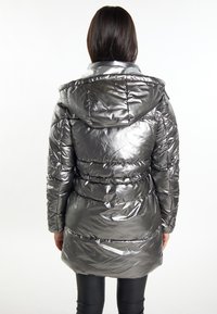 Silberne Puffjacke mit glänzender Oberfläche, Kapuze und elastischem Gummi am Taillenbund. Verfügt über gesteppte Abschnitte und lange Ärmel.