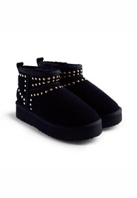 Botas negras de tobillo con tachuelas doradas, suelas gruesas y forro suave, diseñadas para el calor y el estilo.
