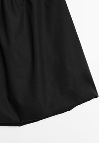 Gonna nera in tessuto liscio, dal design fluido e con un orlo che si allarga delicatamente. Stile minimalista senza motivi visibili.