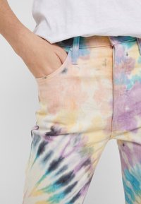 Tief-dye spijkerbroek in pastelkleuren, met een meerkleurig spiraalpatroon. Denim materiaal, met een klassieke vijf-pocketontwerp en riemlussen.