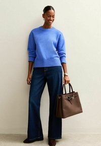 Suéter azul, vaqueros de pierna ancha en denim oscuro, bolso marrón con detalles metálicos, combinado con zapatos oscuros. Textura suave y ajuste entallado.