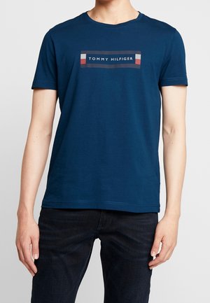 Granatowy bawełniany t-shirt z prostokątnym nadrukiem z napisem „TOMMY HILFIGER” oraz akcentami w kolorach czerwonym, białym i niebieskim. Krótkie rękawy, okrągły dekolt.