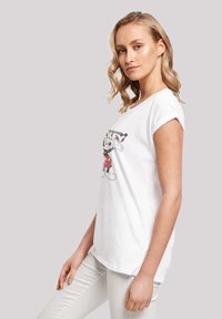 Valge puuvillane T-särk, millel on musta ja punase värviga Mickey Mouse'i graafika. Lühikesed rulliäärega varrukad ja lõdva lõikega disain.