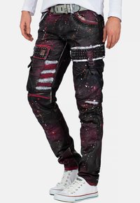 Zwarte en Bordeaux rode cargobroek met verfspetters, meerdere zakken, metalen studs en riemaccenten; taps toelopende pasvorm met textuurstof.