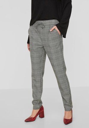 Pantalons gris à carreaux avec une taille à cordon, jambes fuselées et texture douce, complétés par des chaussures à talons rouges.