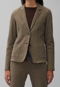 Hnědý kabát v houndstooth vzoru z texturované tkaniny, s dvěma předními kapsami, klopami a dvěma knoflíkovými zapínáními. Vhodný pro smart-casual styl.