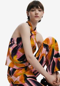 Top a fascia colorato in rosa, arancio e nero con motivo floreale, realizzato in tessuto leggero, abbinato a pantaloni larghi coordinati. Tessuto morbido.