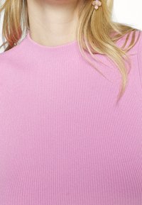 Tajt, ribbat stickad topp i ljusrosa med en hög, rundad halsringning. Texturerat tyg och korta ärmar.