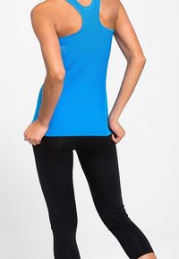 Niebieski sportowy top bez rękawów z designem racerback, wykonany z lekkiego materiału z małymi perforacjami, w połączeniu z czarnymi legginsami 3/4.