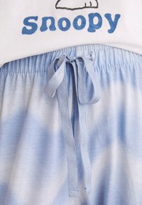 Set di pigiami in cotone composto da una maglietta bianca con una grafica blu "Snoopy" e pantaloni corti blu chiaro con effetto tie-dye e vita con cordoncino.