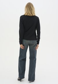 Black long-sleeve top paired with high-waisted, wide-leg blue jeans. The jeans feature a classic five-pocket design and frayed hems.