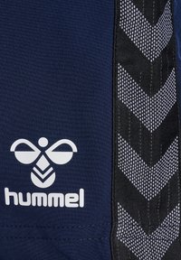 Marinefarbene Sportshorts mit schwarzem Seitenpaneel, das ein weißes Chevron-Muster aufweist. Weißes "hummel"-Logo ist deutlich auf der Vorderseite angebracht.