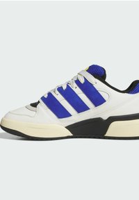 White sneaker with blue suede accents, three white stripes, and a textured black outsole. Features a mesh tongue and round laces.